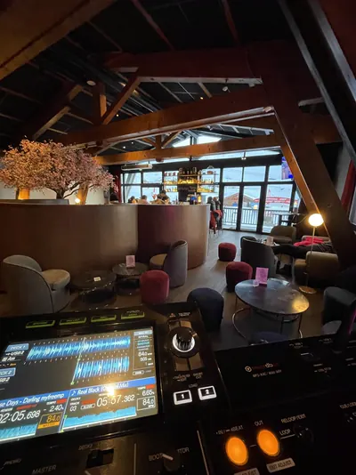 Table de mixage face au salon d'un bar de montagne, charpente en bois